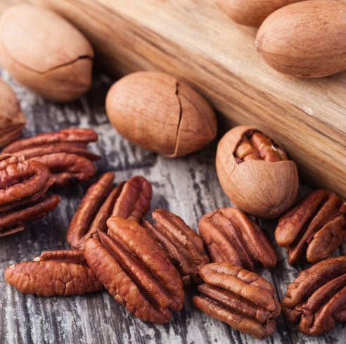Pecans with shells on rustic wooden background.